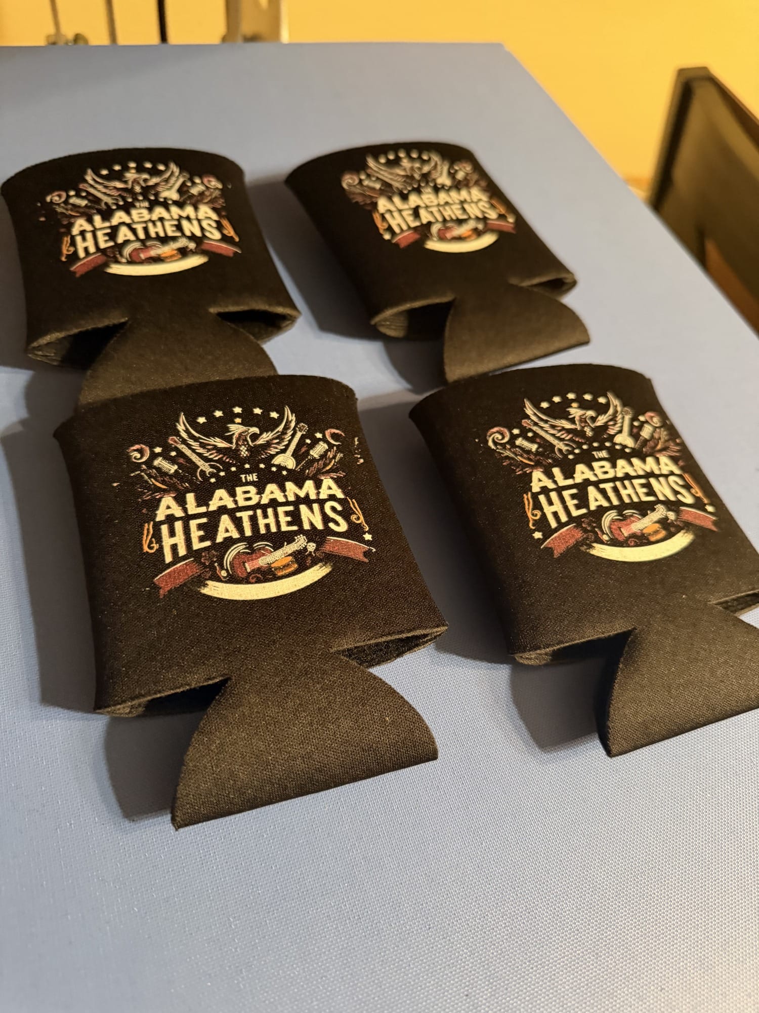 Four black Alabama Heathens koozies with the band’s white logo.